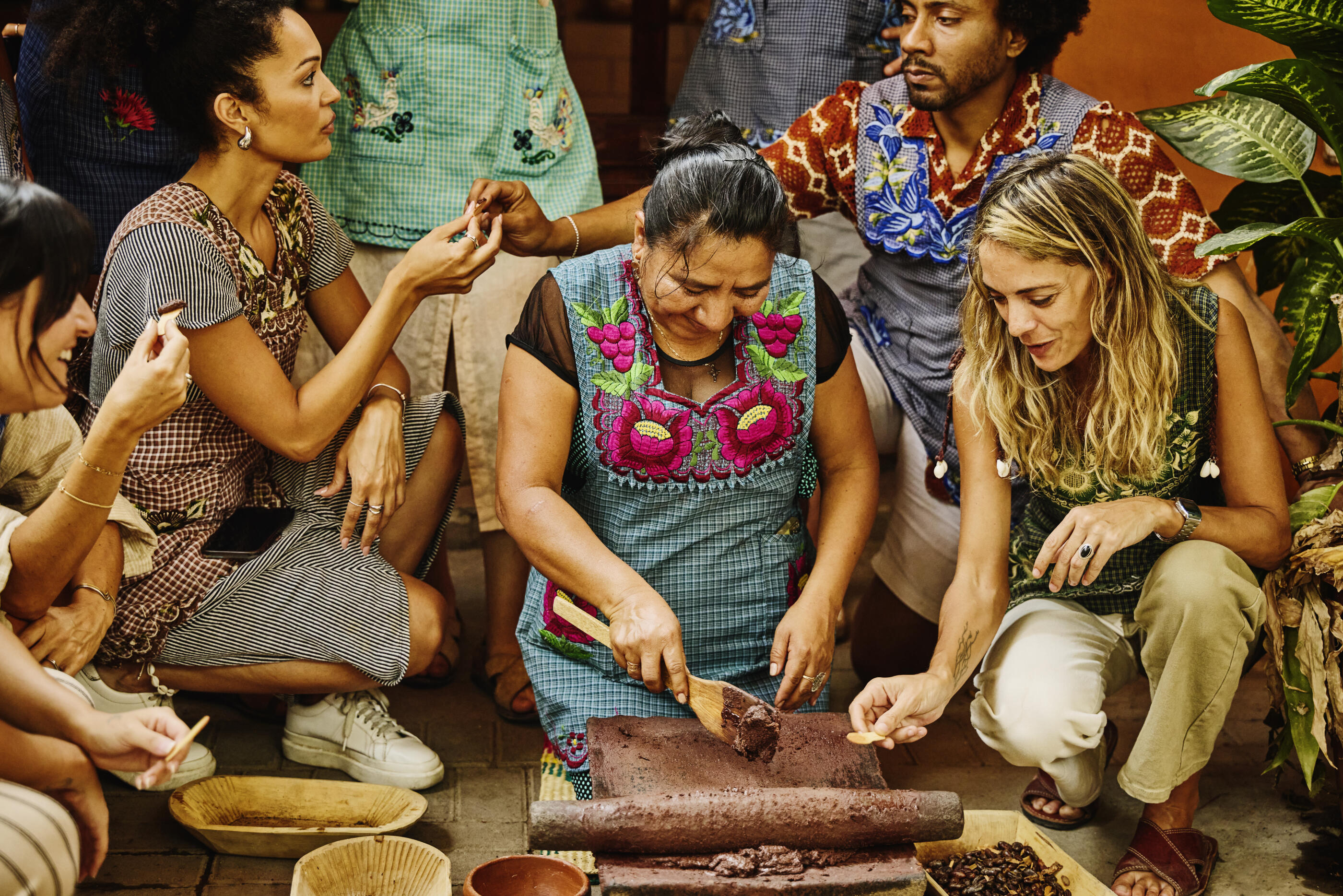 Medium wide shot tourists tasting freshly made Oaxacan hot chocolate paste during cooking class