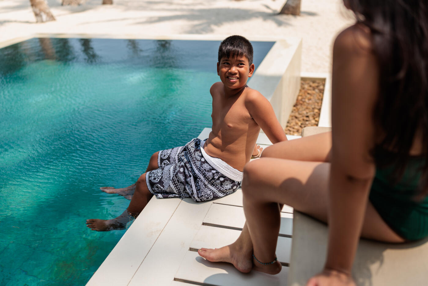 A mother and son relax by the pool at a luxury resort, enjoying their time together. In Koh Phangan, Thailand.