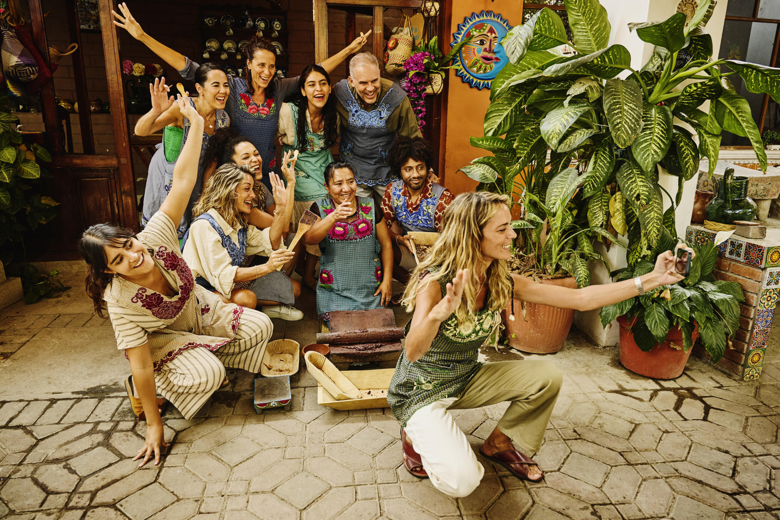 Wide shot woman taking group selfie at experiential cooking class