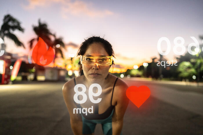 Portrait of a young adult woman with futuristic glasses analyzing data while exercising outdoors