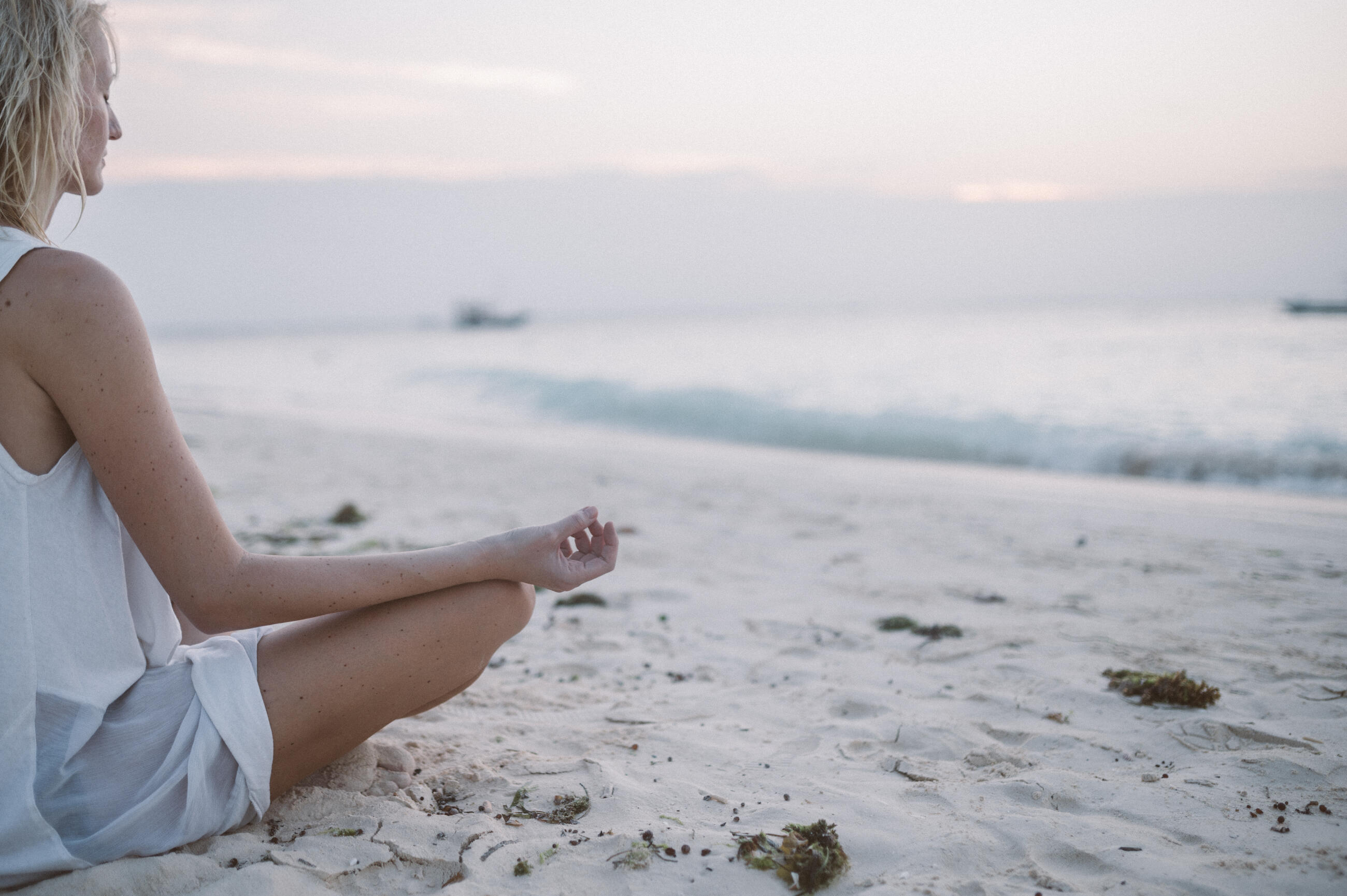 Young woman sitting on the beach and meditating