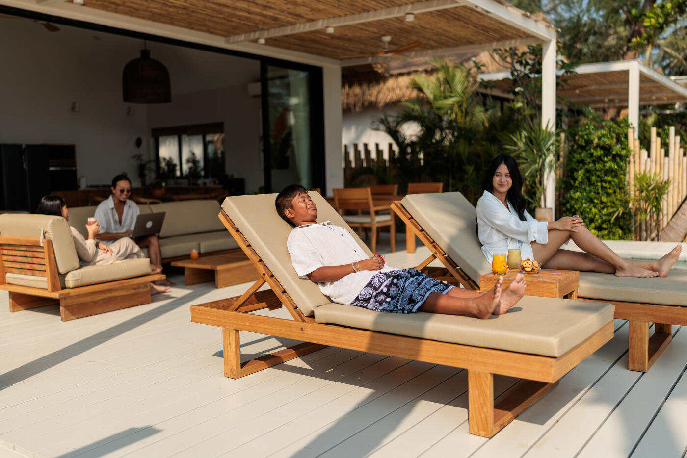 Children lie comfortably on lounge chairs, enjoying a peaceful moment while their parents relax behind them.