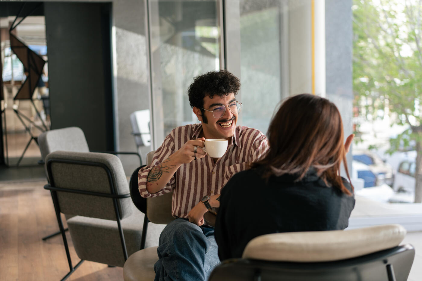 Two young adults enjoying a coffee break and chatting in a modern cafe