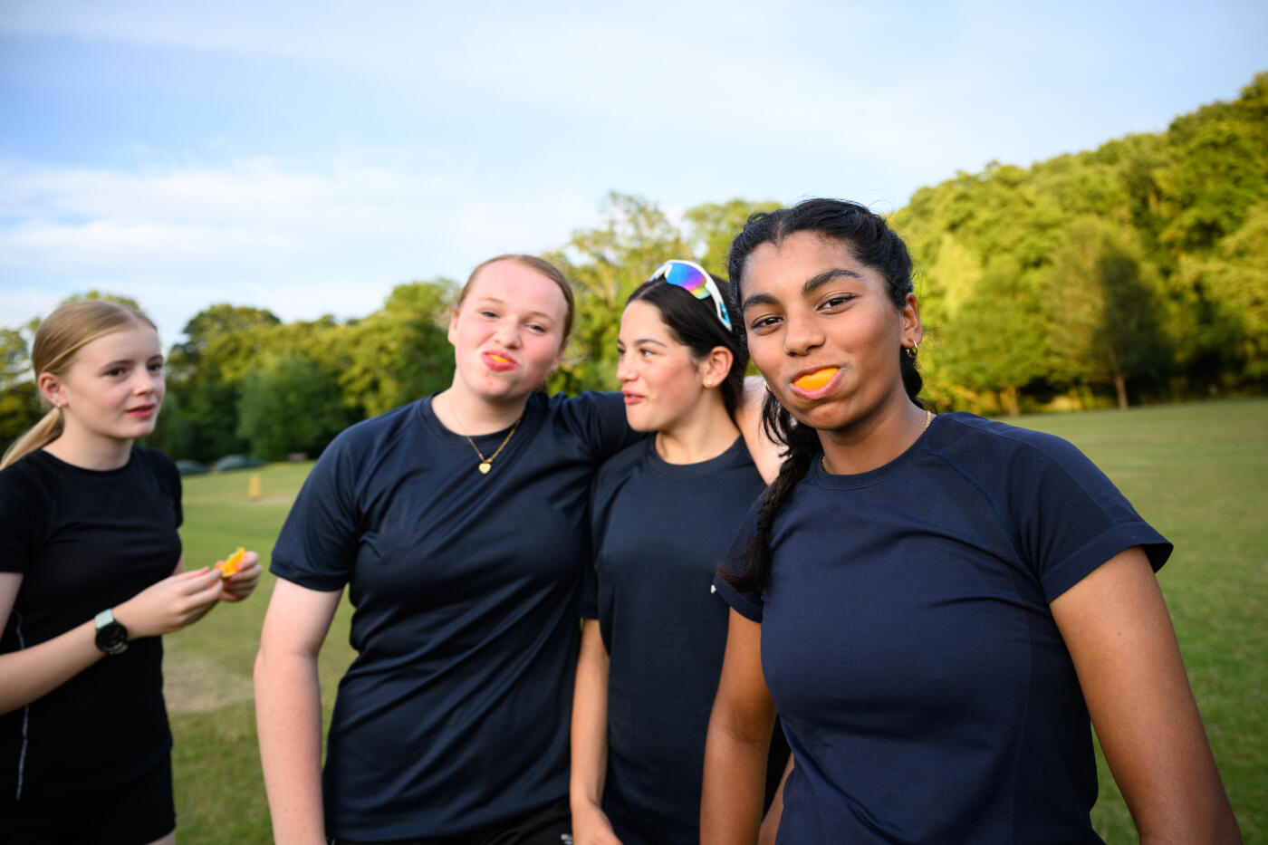 Teenage girls cricket team practicing outdoors on green grass cricket itch in summer