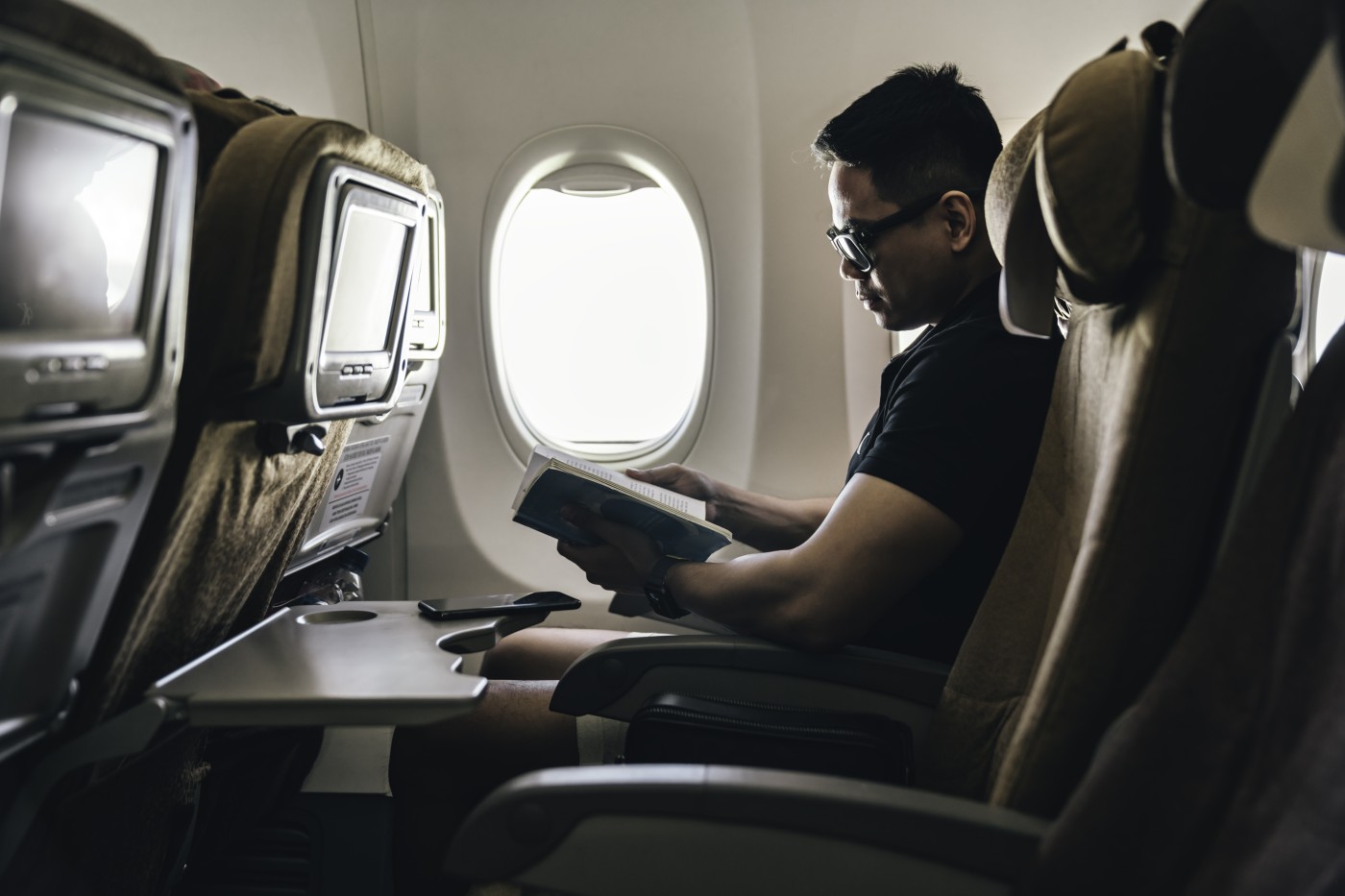 man reading a book on airplane