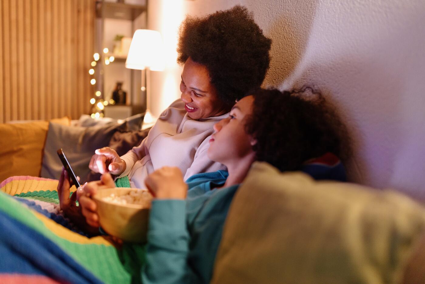 Mother and son sitting on the couch and surfing the net at night