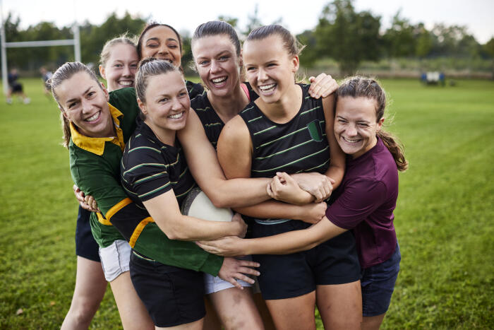 Happy women's rugby team on sports field