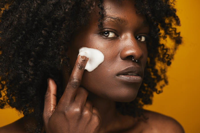 Young adult woman applying facial cleanser for healthy skin