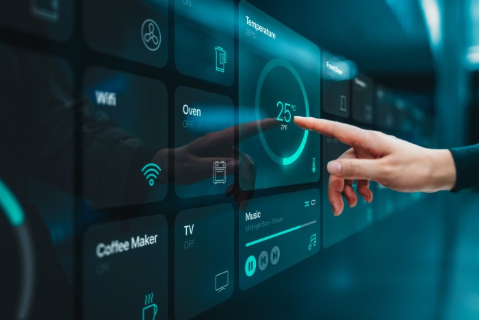 Close up of woman's hand setting up intelligent home system, controlling smart home appliances with control panel of a smart home. Home automated system controlled from a dashboard. Smart living. Lifestyle and technology. Smart home technology concept