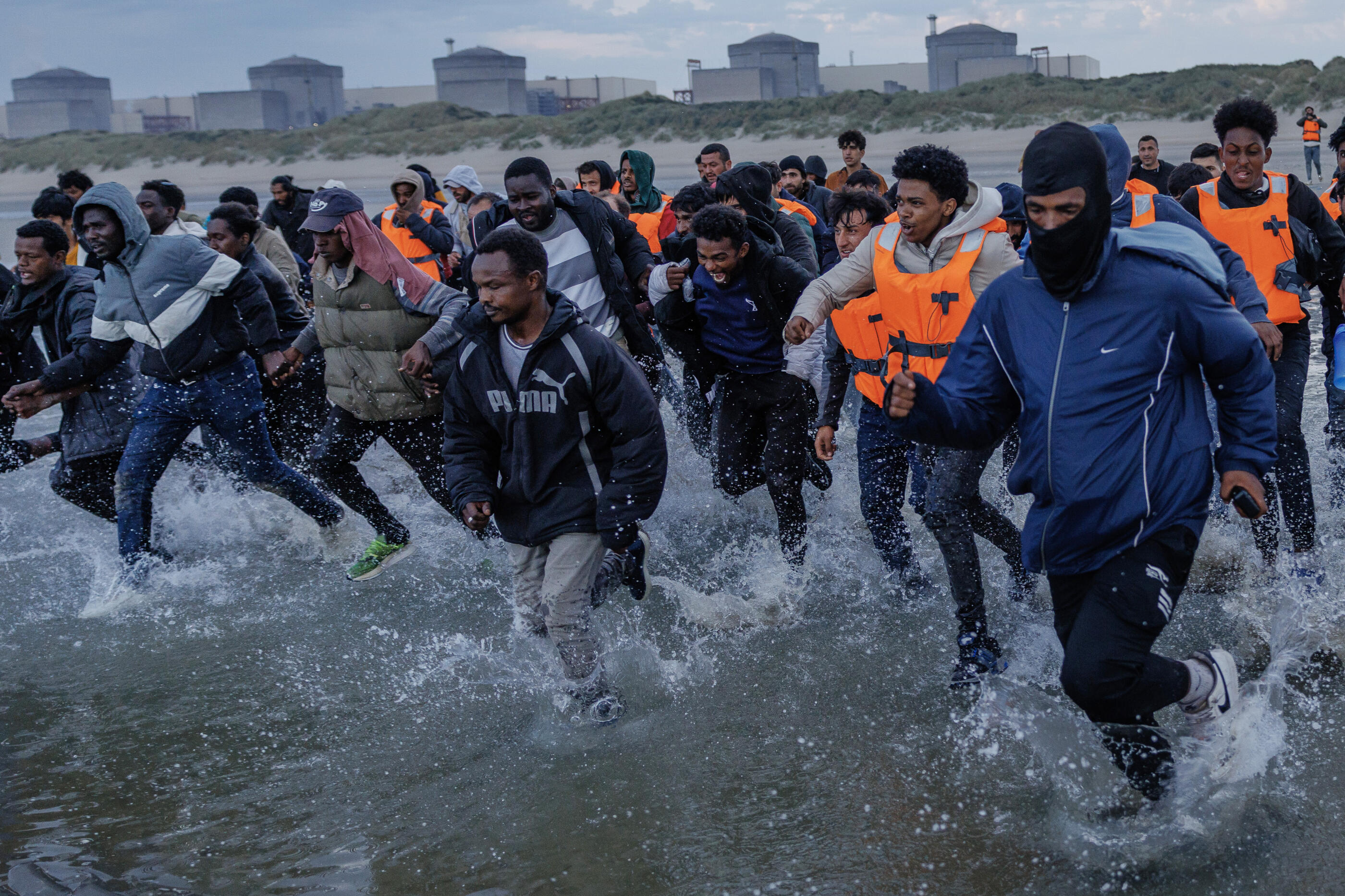 GRAVELINES, FRANCE - AUGUST 12: Migrants wade into the sea in an attempt to board a small boat on August 12, 2025 in Gravelines, France. More than 50000 small boat migrants have now crossed the English Channel since Labour came to power last July. Last week the UK and France began implementing the so-called 'one-in, one-out' treaty, which was agreed during French President Emmanuel Macron's state visit last month, in an effort to curb illegal migration across the English Channel. Under the pilot scheme, a proportion of undocumented people arriving to the UK in small boats will be returned to France, in exchange for the same number of legitimate asylum seekers who may have family ties in the UK. (Photo by Dan Kitwood/Getty Images)