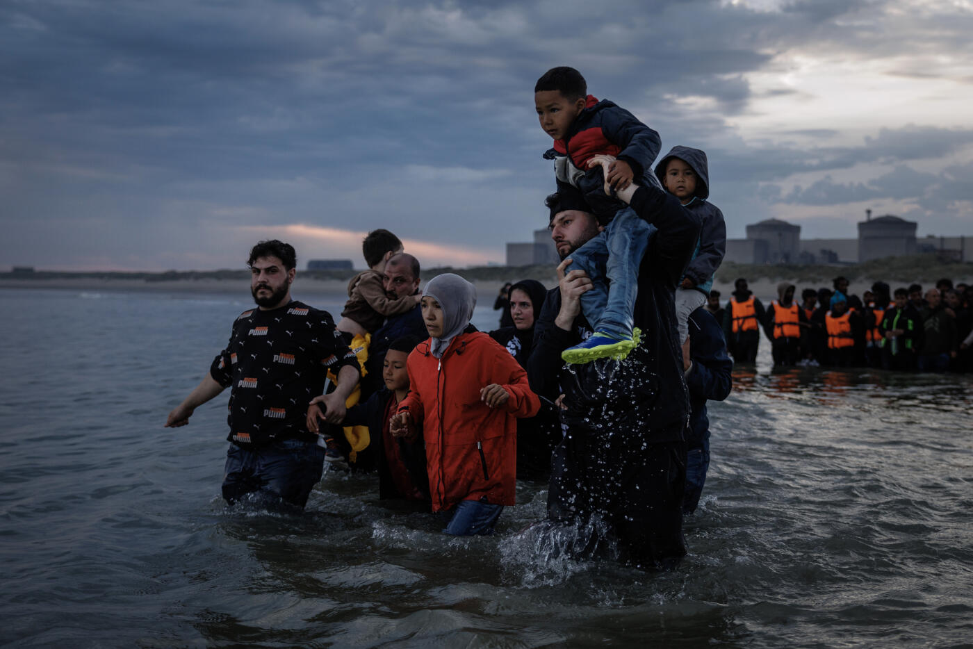 GRAVELINES, FRANCE - AUGUST 12: Migrant families wade into the sea in an attempt to board a small boat on August 12, 2025 in Gravelines, France. More than 50,000 small boat migrants have now crossed the English Channel since Labour came to power last July. Last week the UK and France began implementing the so-called 'one-in, one-out' treaty, which was agreed during French President Emmanuel Macron's state visit last month, in an effort to curb illegal migration across the English Channel. Under the pilot scheme, a proportion of undocumented people arriving to the UK in small boats will be returned to France, in exchange for the same number of legitimate asylum seekers who may have family ties in the UK.  (Photo by Dan Kitwood/Getty Images)