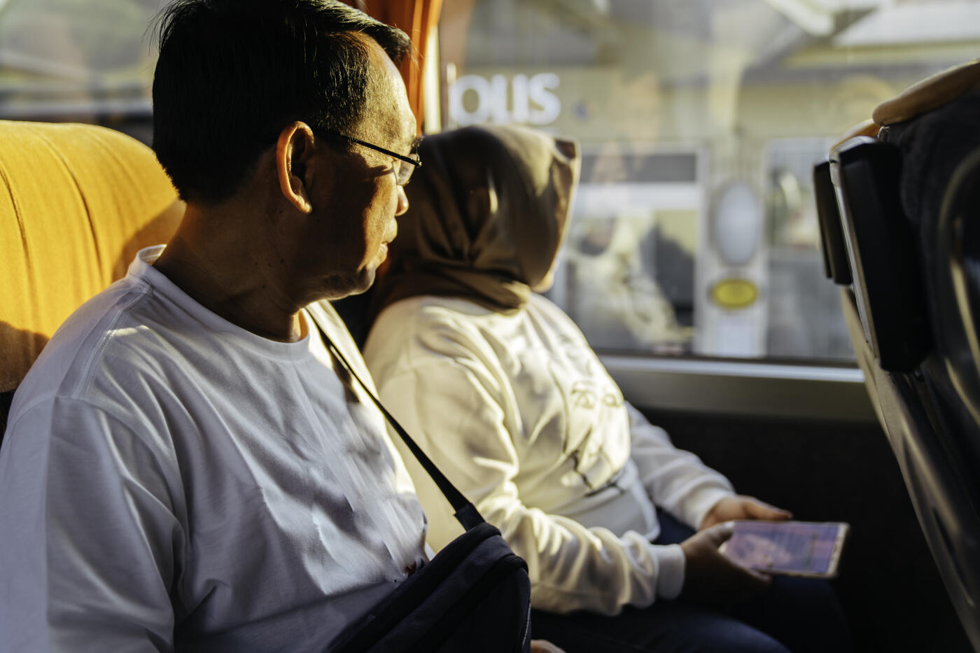 senior couple  leans back to enjoy the view whilst taking a bus trip.