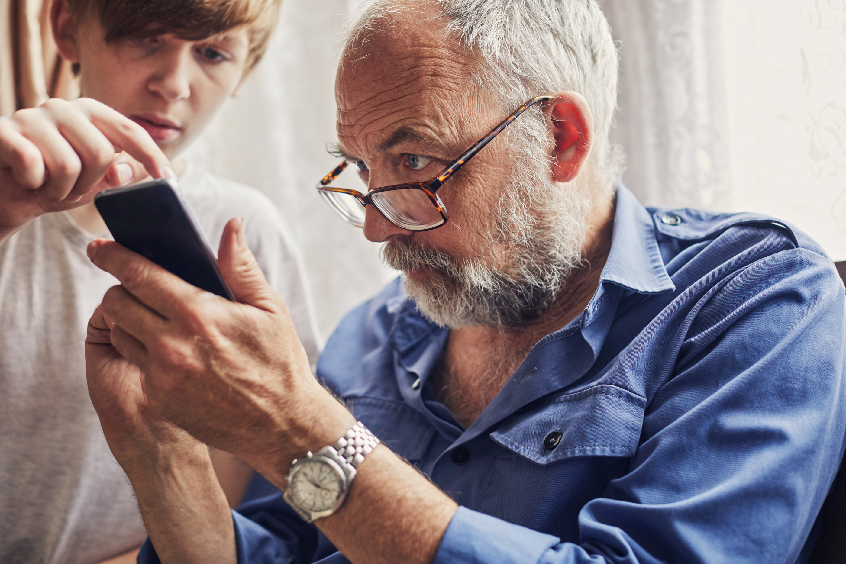 Teenage boy using a smartphone with his grandfather