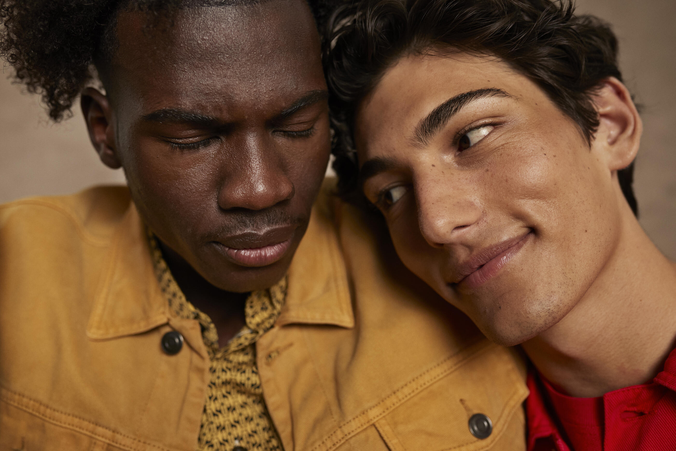 Smiling young man leaning on male friend's shoulder