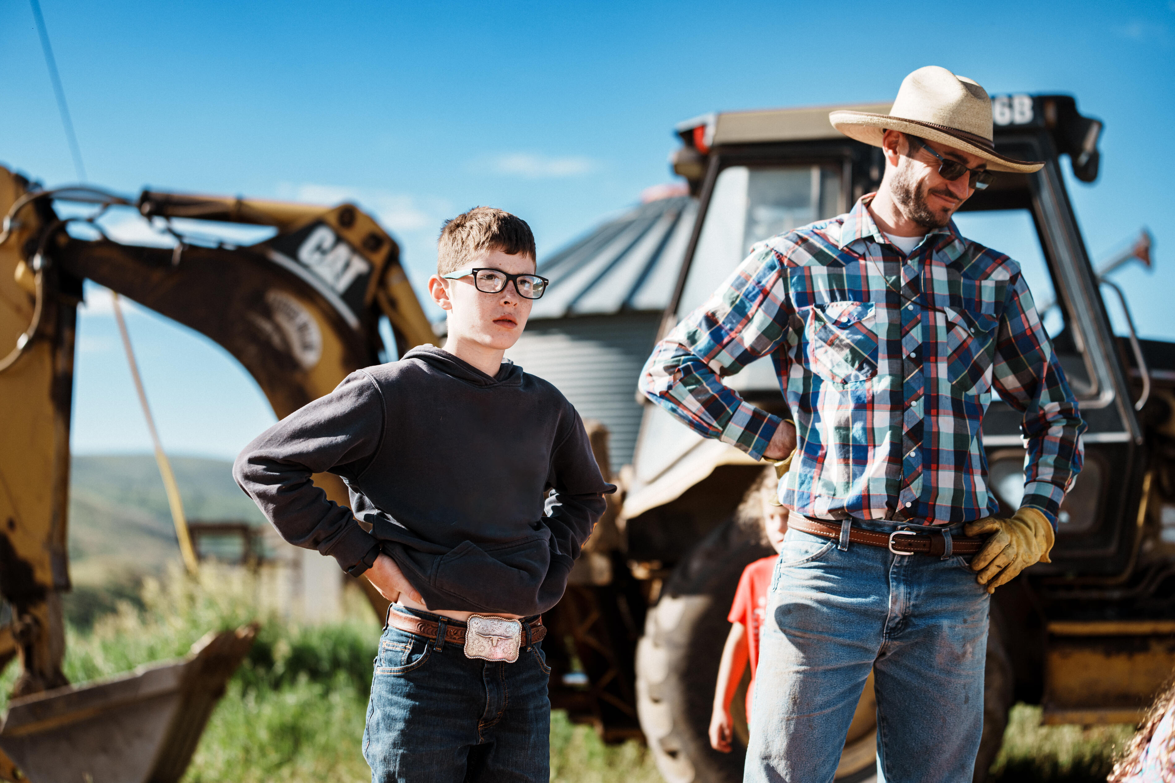 Father and Son Beside Backhoe on Family Ranch