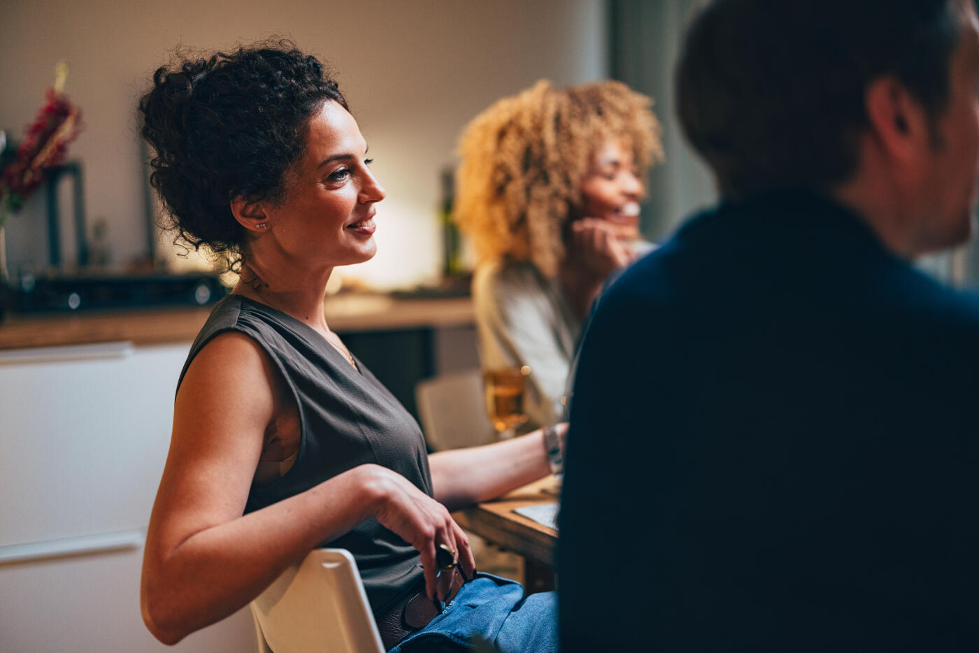 Group of multi-ethnic friends talking and laughing while having dinner together at dining table.
