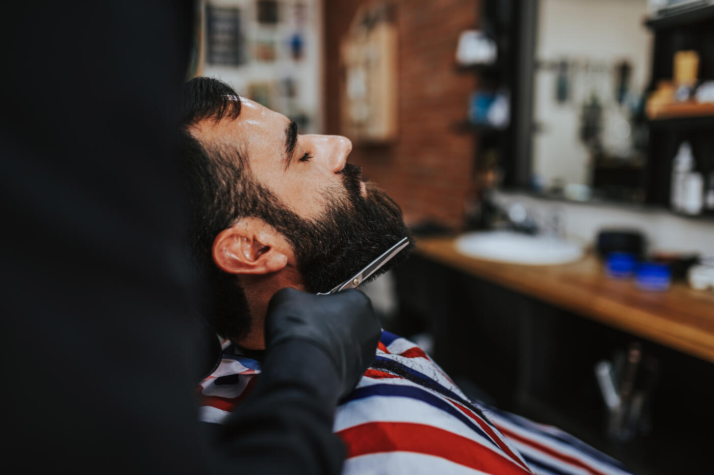 Young beard man visiting barber shop. Trendy and stylish beard styling and cut.
