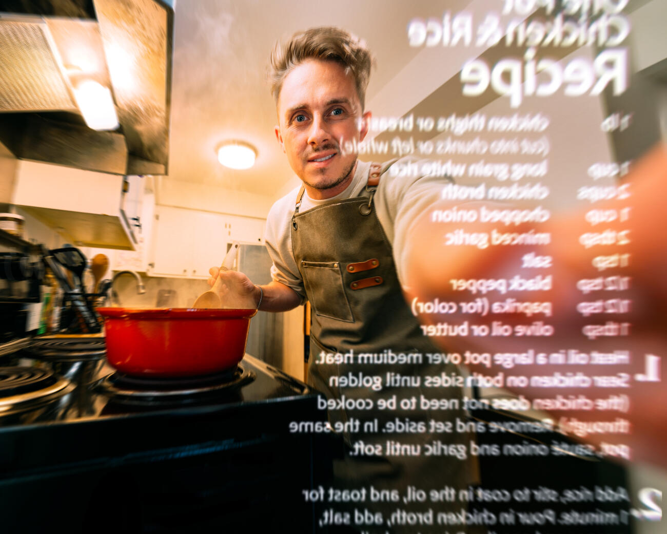 Young Man Reaching to Scroll a Digital Online Recipe Cookbook on a Smart Home Kitchen Tablet in a Small Home Apartment Kitchen while Cooking