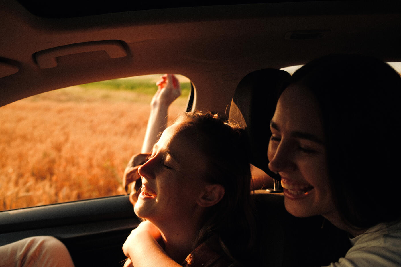 Photo of smiling sisters enjoying in the car during a road trip