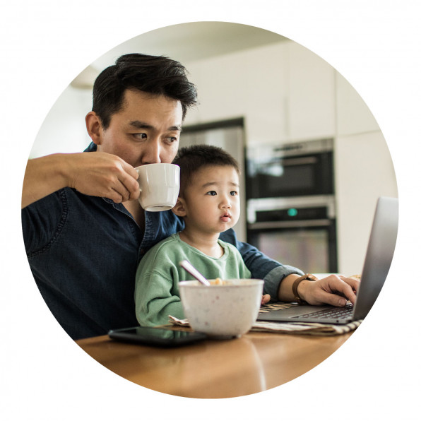 Man drinking coffee with young child while working