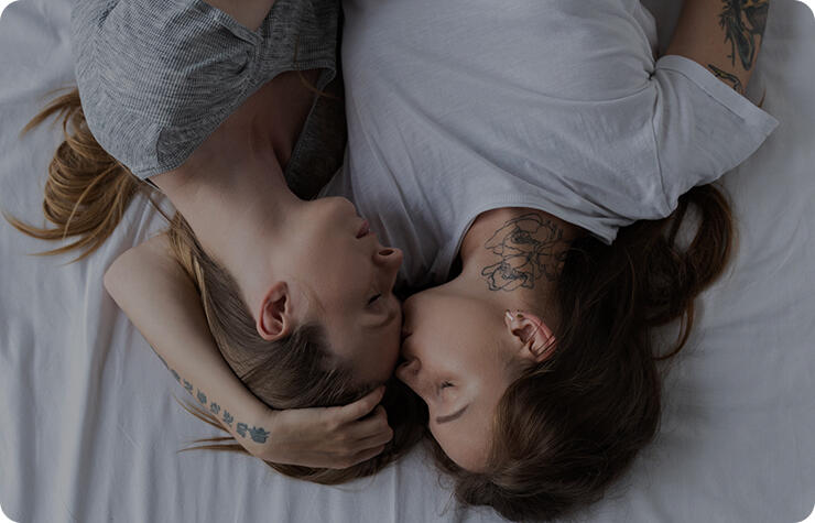 nhìn từ trên xuống hai người đồng tính nữ đang ôm và hôn nhau trên giường