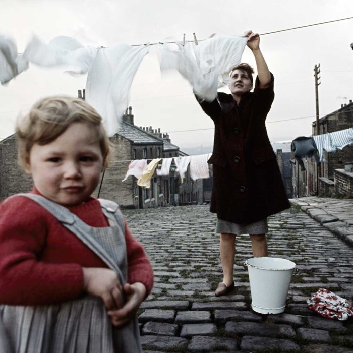 A woman strings her washing across the street paved with setts in Halifax, West Yorkshire in 1965